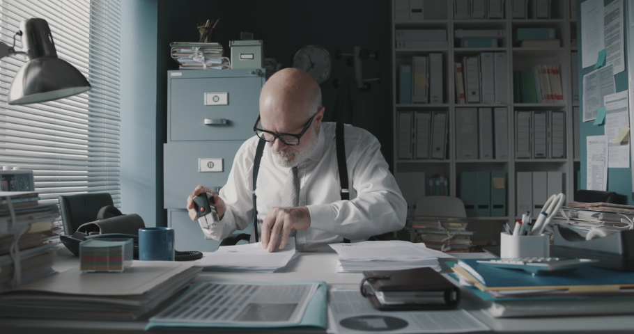 Efficient employee stamping a pile of paperwork, repetitive task concept | Shutterstock HD Video #1067836223