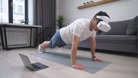 Man in virtual reality glasses performs a workout and push-ups, sports using modern technology in self-isolation.