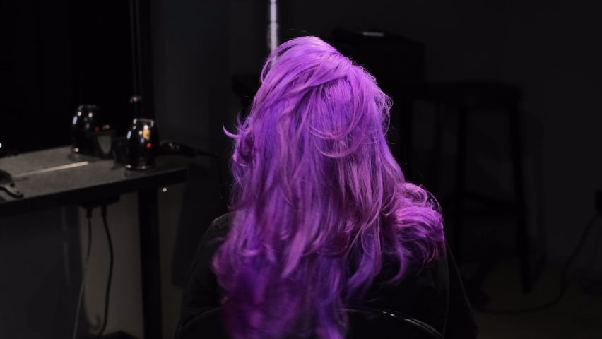 Woman sitting in a beauty salon with pink-purple hair color, curly pretty hair   | Shutterstock HD Video #1067842355