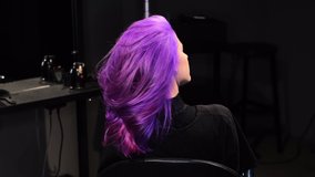 Woman sitting in a beauty salon with pink-purple hair color, curly pretty hair   - Powered by Shutterstock - Get 15% off with code: PIKWIZARD15