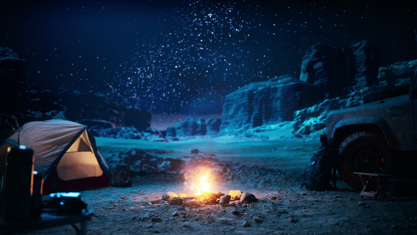 People Camping at Night in the Canyon, Preparing to Sleep in the Tent. Campfire barely Burning, Truck nearby. Amazing Natural Landscape View with Marvelous Bright Milky Way Stars Shining on Mountains Royalty-Free Stock Footage #1067850659