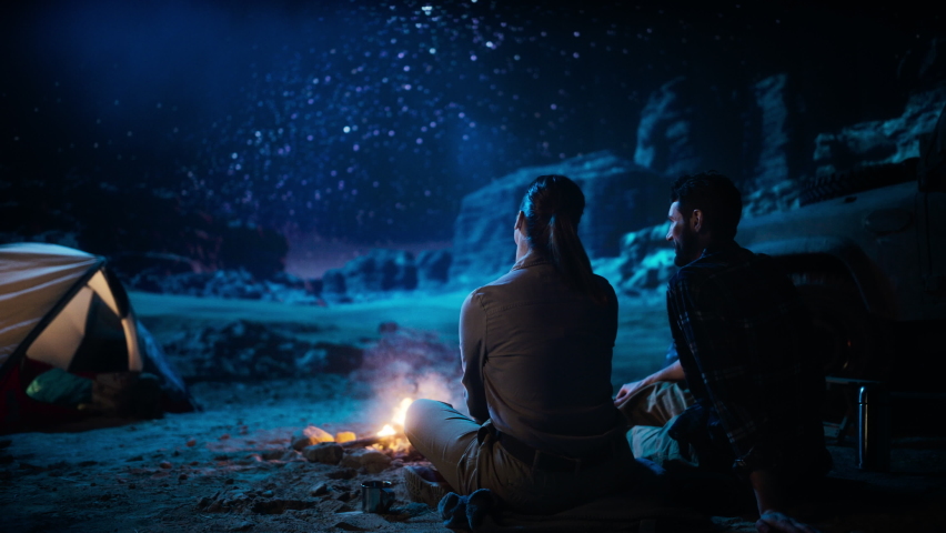 Happy Couple Nature Camping in the Canyon, Sitting by Campfire Watching Night Sky with Milky Way Full of Bright Stars. Two Travelers In Love On a Romantic Vacation Trip. Zoom Out Back View Shot | Shutterstock HD Video #1067850668
