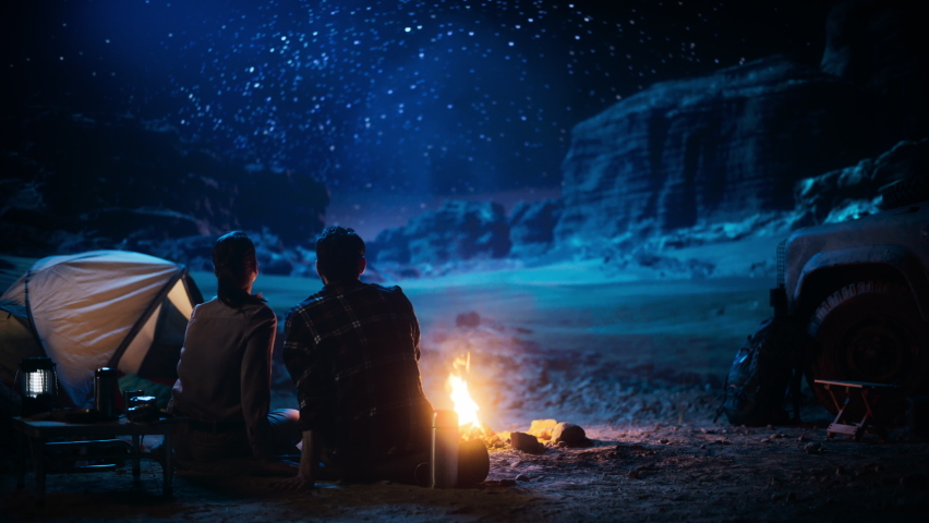 Happy Couple Camping in the Canyon, Sitting Watching Campfire and Starry sky Together, She Rests Her Head on His Shoulder. Two Traveling people On Inspirational Vacation Trip Marvel at Milky Way Stars Royalty-Free Stock Footage #1067850689