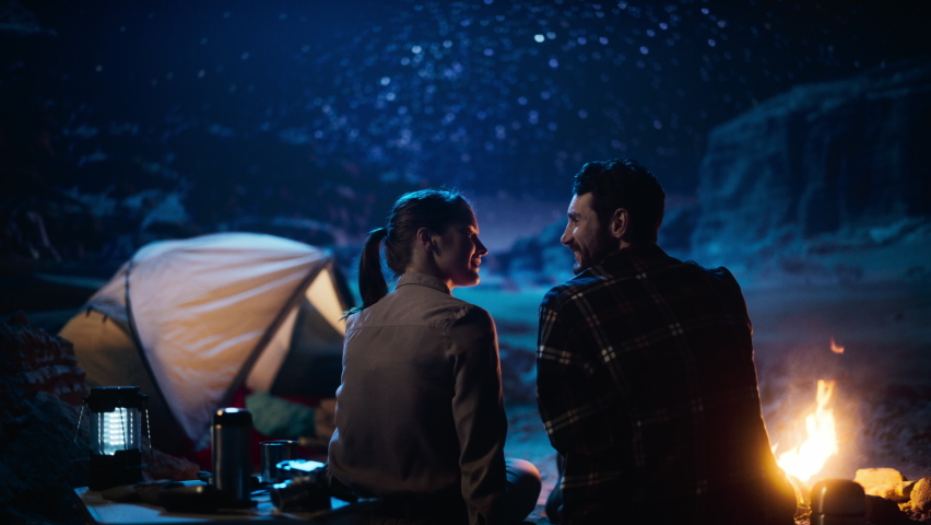 Happy Couple Camping in the Canyon, Sitting Watching Campfire and Starry sky Together, She Rests Her Head on His Shoulder. Two Traveling people On Inspirational Vacation Trip Marvel at Milky Way Stars