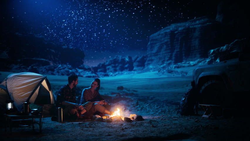 Happy Couple Camping in the Canyon, Sitting Watching Campfire and Starry sky Together, She Rests Her Head on His Shoulder. Two Traveling people On Inspirational Vacation Trip Marvel at Milky Way Stars