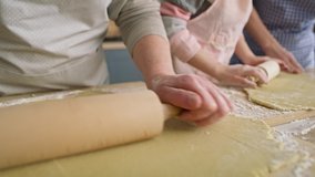 Close up video of three women rolling dough. 