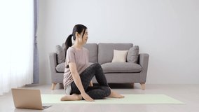 sporty asian woman stretching in the living room