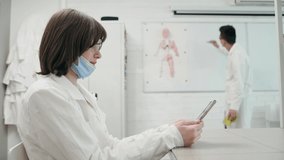 A young schoolgirl sits at a biology, chemistry or medicine lesson with a mobile phone in her hands. the teacher makes a remark. The girl puts on the mask - Powered by Shutterstock - Get 15% off with code: PIKWIZARD15