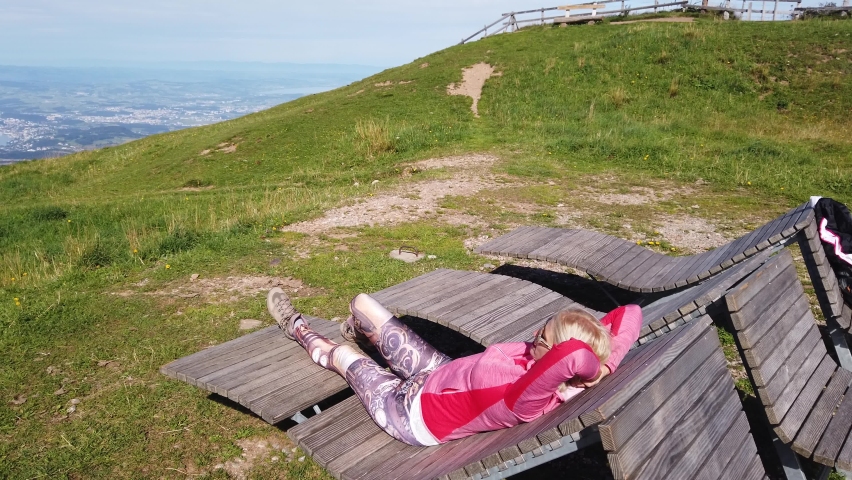 Tourist woman sleeping on deckchair from a top of Rigi-Kulm, Mount Rigi. Tourist enjoys outdoor activities of Rigi Railways, the queen of mountains, one of the most popular excursions in Switzerland.