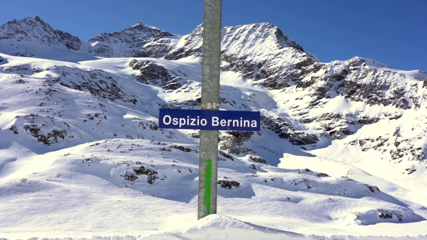 Switzerland Alps , Poschiavo - February 2021 Bernina Express,  Ospizio Bernina station -  Unesco world heritage - Rhaetian railway with snow in a sunny day with blue sky