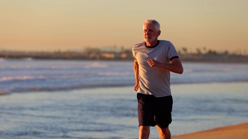 64 year old man getting his exercise at the beach at sunset. Slow Motion.