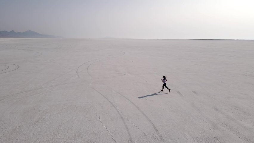 Aerial shot of an Asian woman jogging across the Bonneville Salt Flats flats in Utah