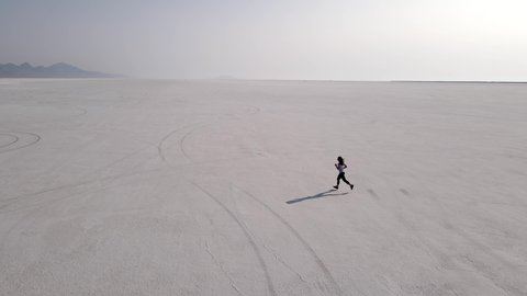 Aerial shot of an Asian woman jogging across the Bonneville Salt Flats flats in Utah Stockvideo