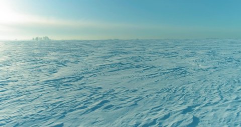 Drone aerial view of cold winter landscape arctic field, trees covered with frost snow, ice river and sun rays over horizon. Extreme low temperature weather. Stockvideo
