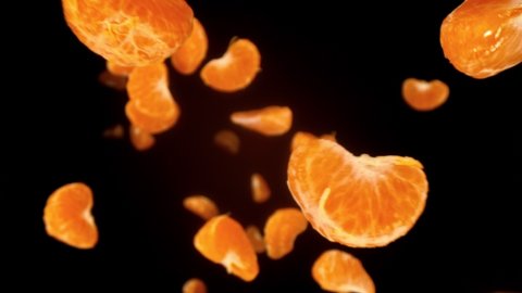 Fresh Tangerine Pieces Falling on Black Background. Super Slow Motion, Wide Angle View.