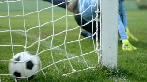 Football soccer game. Detail shot of a goal. Goalkeeper jumping for the ball, but missing to save the door, 4k slow motion