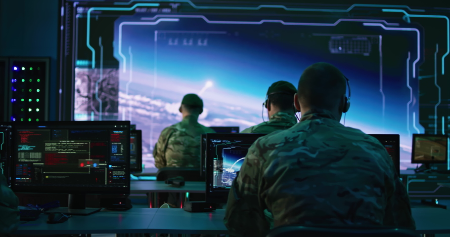 Pan left view of anonymous military men using computers to launch nuclear missiles in modern command center during world war