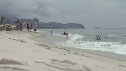 Sea with small waves at Barra da Tijuca Beach and some people having fun, on a partially cloudy day. Located in Rio de Janeiro