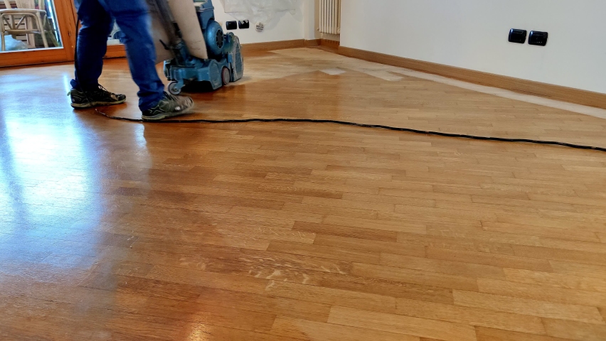 Worker man sanding wooden floor of parquet, with pad sander machine in an empty room during a renovation. Sand and refinish hardwood floors. Royalty-Free Stock Footage #1067886608