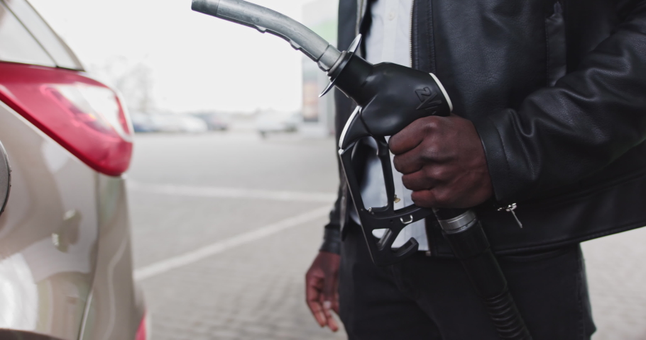 Closeup of man filling benzine gasoline fuel in car at gas station. African American Man Refueling Car At Gas Station. Fuel, gas station, petrol prices concept. Gasoline, gas, fuel, petroleum concept