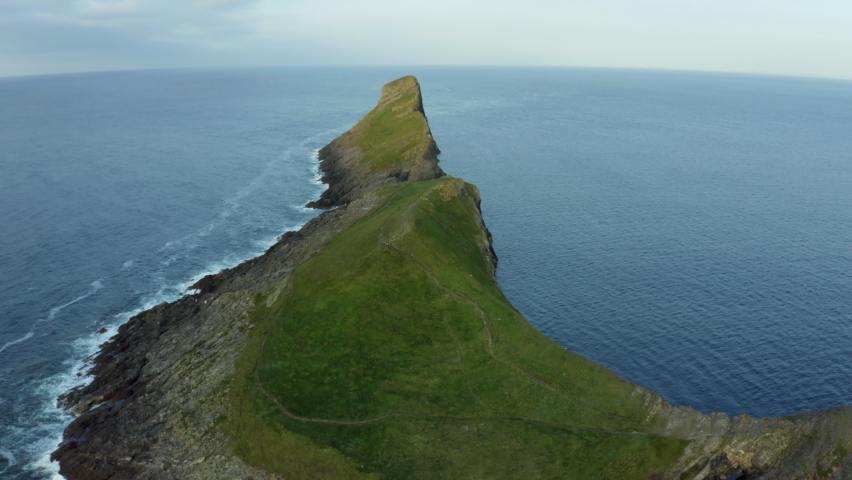 Drone aerial footage of Worms head in Rhossili bay in the Gower peninsula in Swansea, Wales, with huge cliffs