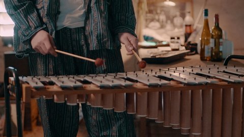 Man plays the metallophone to make music in a blue paisley suit
