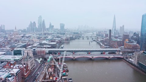 London snow aerial dolly forward drone shot towards iconic city centre and river thames