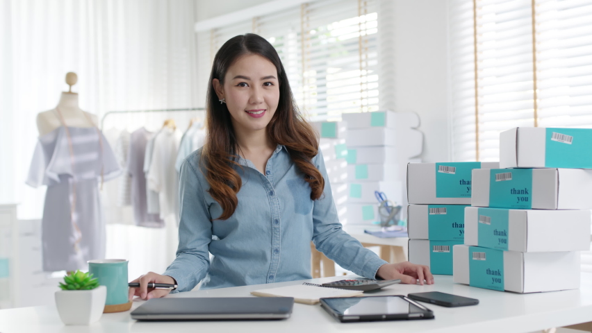 Portrait young attractive asia female owner startup business look at camera work happy with box at home prepare parcel delivery in sme supply chain, procurement, omnichannel ecommerce online concept. | Shutterstock HD Video #1067899478