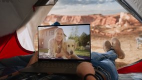 POV Footage of a Tourist Making a Video Call with a Friend Playing with Happy Dog on Laptop Computer. Traveller Resting in a Tent on Top of a Rocky Mountain. Adventurous Hiker Living in Nature.