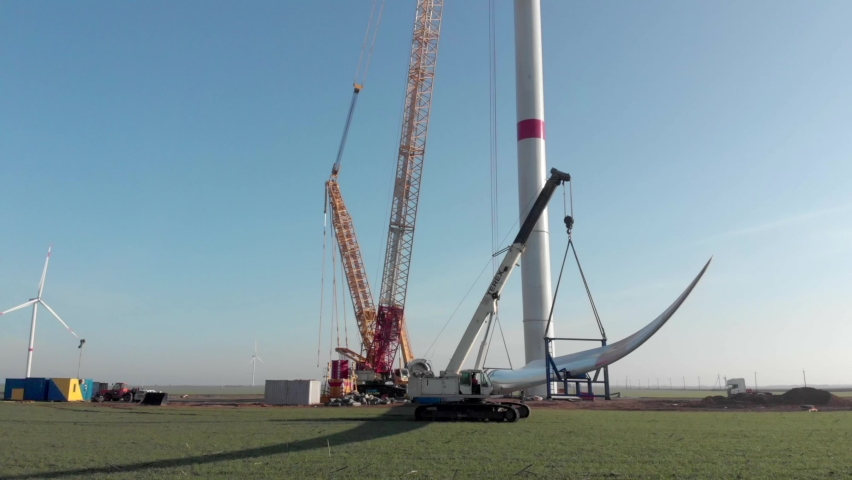 Building process of wind energy power tower mill, under construction. Transportation, installation of rotor blades. Green, clean, renewable energy. Aerial footage. Royalty-Free Stock Footage #1067907164