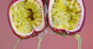 Close up video passion fruit juice flowing down from juicy pulp on pink studio background, exotic vegan healthy eating