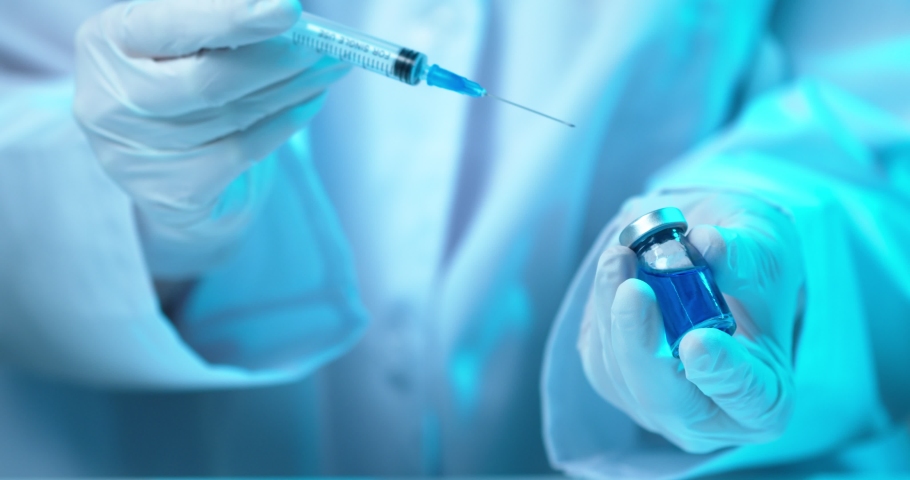 Doctor and shot for injection. Close up video, physician hands filling up syringe with blue vaccine for vaccination | Shutterstock HD Video #1067908001