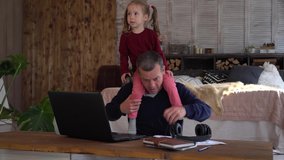 Remote working with a family during COVID-19 Lockdown. Stressed dad Works from Home with Kid. Online business and parenting. Financial crisis. Little daughter jumps and plays noisily  - Powered by Shutterstock - Get 15% off with code: PIKWIZARD15