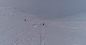 Aerial view: four snow bikers on snowmobiles. an epic video of a friendly team of snowmobilers riding through a large snow-white canyon high in the mountains at dawn