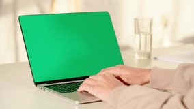 cropped view of woman typing on laptop with green screen