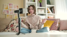 Beautiful teenage girl recording video blog with her smartphone. Young vlogger shooting vlog at home. Teen influencer creating content for her social media account. Social media and blogging concept.