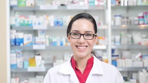 women pharmacist smiling confident and looking at the camera in modern pharmacy. Slow motion
