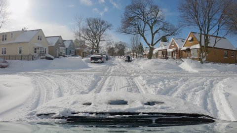 CHICAGO, USA - CIRCA FEBRUARY 2021: POV driving on one way street with people shoveling heavy snow from the the cars parked on the side, residential area