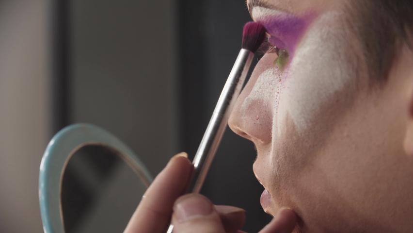Drag artist - young man applying purple eyeshadows under his brow Royalty-Free Stock Footage #1067931854