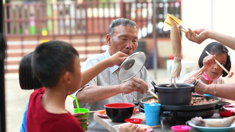 Family grandfather and children eating food party on night of summer holiday, seafood and meat grilling and roasting on pan, happy Asian people family of kids in party, delicious and tasty food menu
