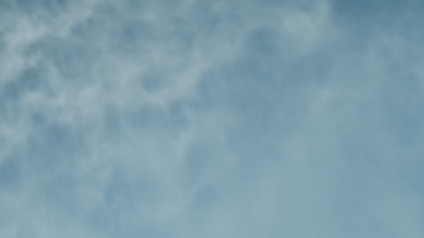 Artificial snow close-up, slow motion, abstract background of sprayed water haze in frost on suny blue sky. Snow cannon blows white powder falls in waves. Snow production technology by gun in winter