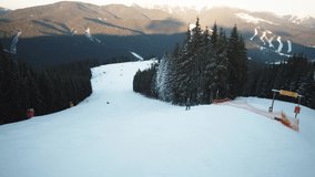 Aerial view of skier glying on snowy slopes ride downhill enjoying winter vacation. Ski lift footage. Skiing in Bukovel resort, Carpathian mountains.