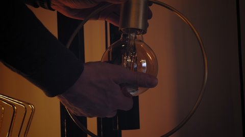 screwing the bulb. incandescent lamp. close-up. man replacing, changing bulb with Edison filament, screwing it into lamp holder and lit it up.
