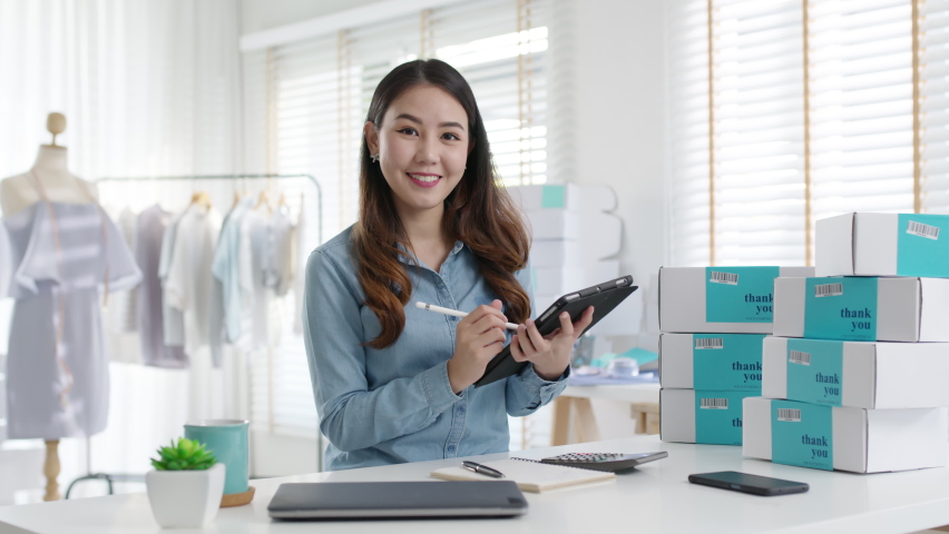 Portrait young attractive asia female owner startup business look at camera work happy with box at home prepare parcel delivery in sme supply chain, procurement, omnichannel commerce online concept. | Shutterstock HD Video #1067943188
