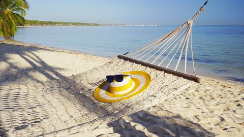 Empty hammock between palm trees on tropical beach by the sea