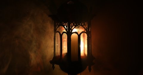 Arabic lantern with candle at night for Islamic holiday. Muslim holy month Ramadan. The end of Eid and Happy New Year. Copy space on dark background.