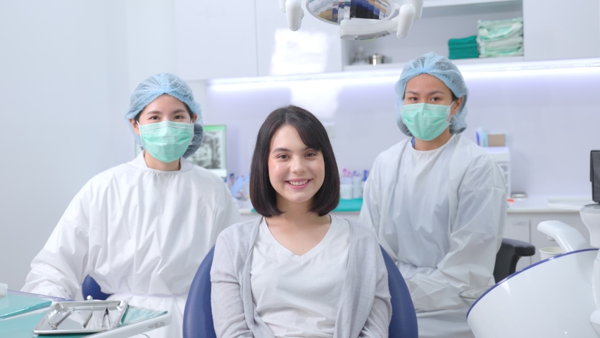 Portrait of Caucasian girl patient smiling, sitting on dental chair waiting for medical service from dentist and assistant. Female doctor and assistant ready to provide oral care treatment services. | Shutterstock HD Video #1067949527