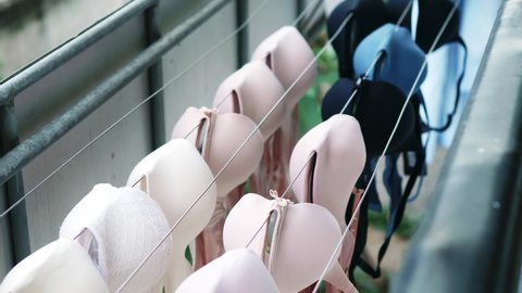 Selective focus of women's various colors bras that are being dried outdoors from weekly washing.