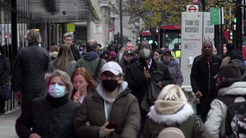London , United Kingdom (UK) - 12 02 2020: People wearing face masks walk past a social distancing sign during the Coronavirus pandemic
