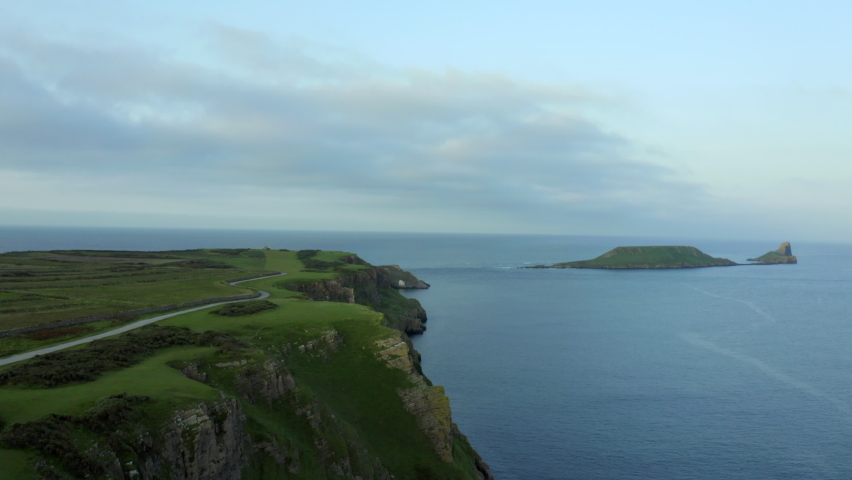 Drone aerial footage of huge cliffs in Rhossili bay in Gower peninsula, Swansea in South Wales